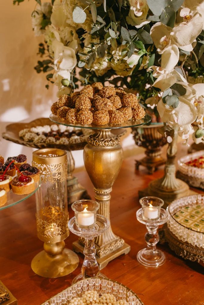 close-up-of-desserts-at-a-wedding-26774590 Luxurious dessert table featuring golden trays and a vibrant floral centerpiece, perfect for events.